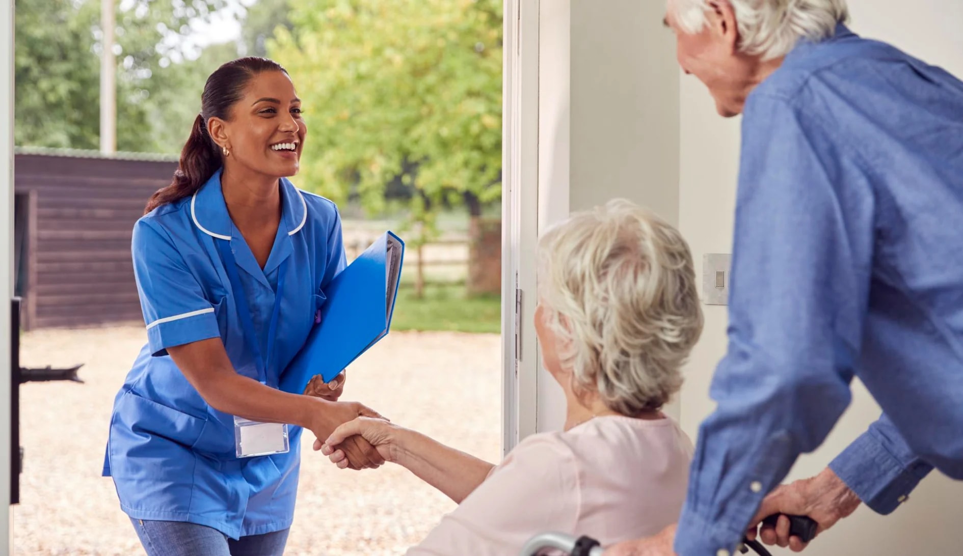 A nurse greeting an older woman at her front door.