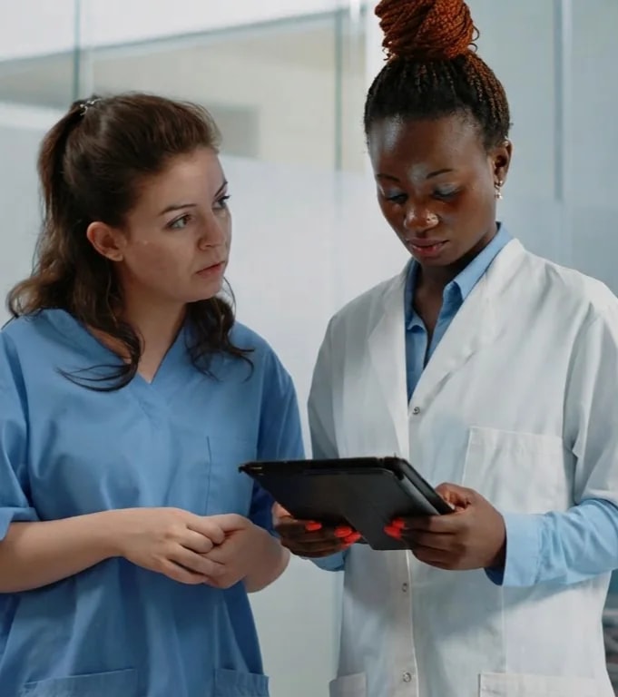 Two clinicians going over notes on a tablet together.