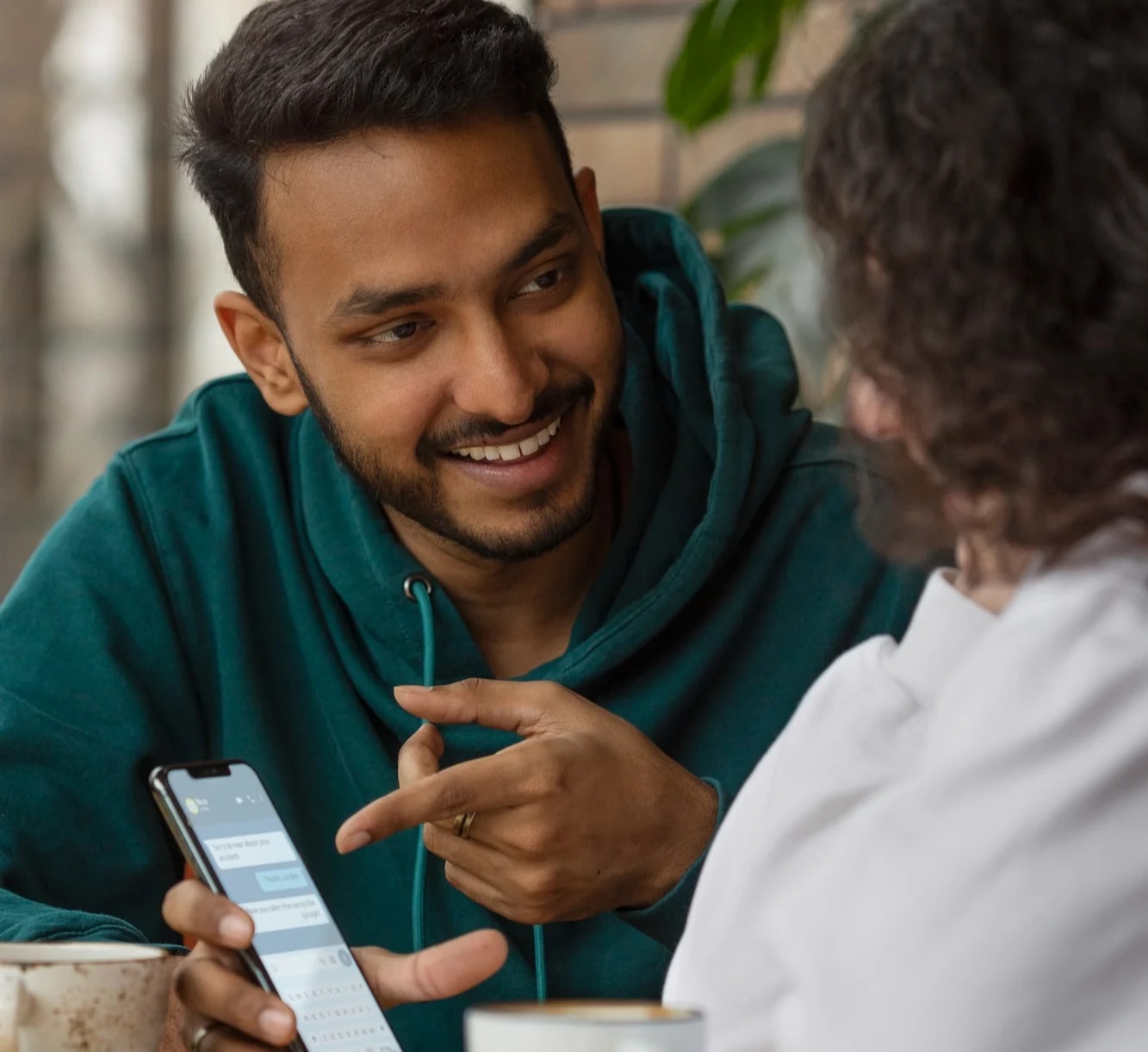 A young man showing something on his phone to a relative, both laughing.
