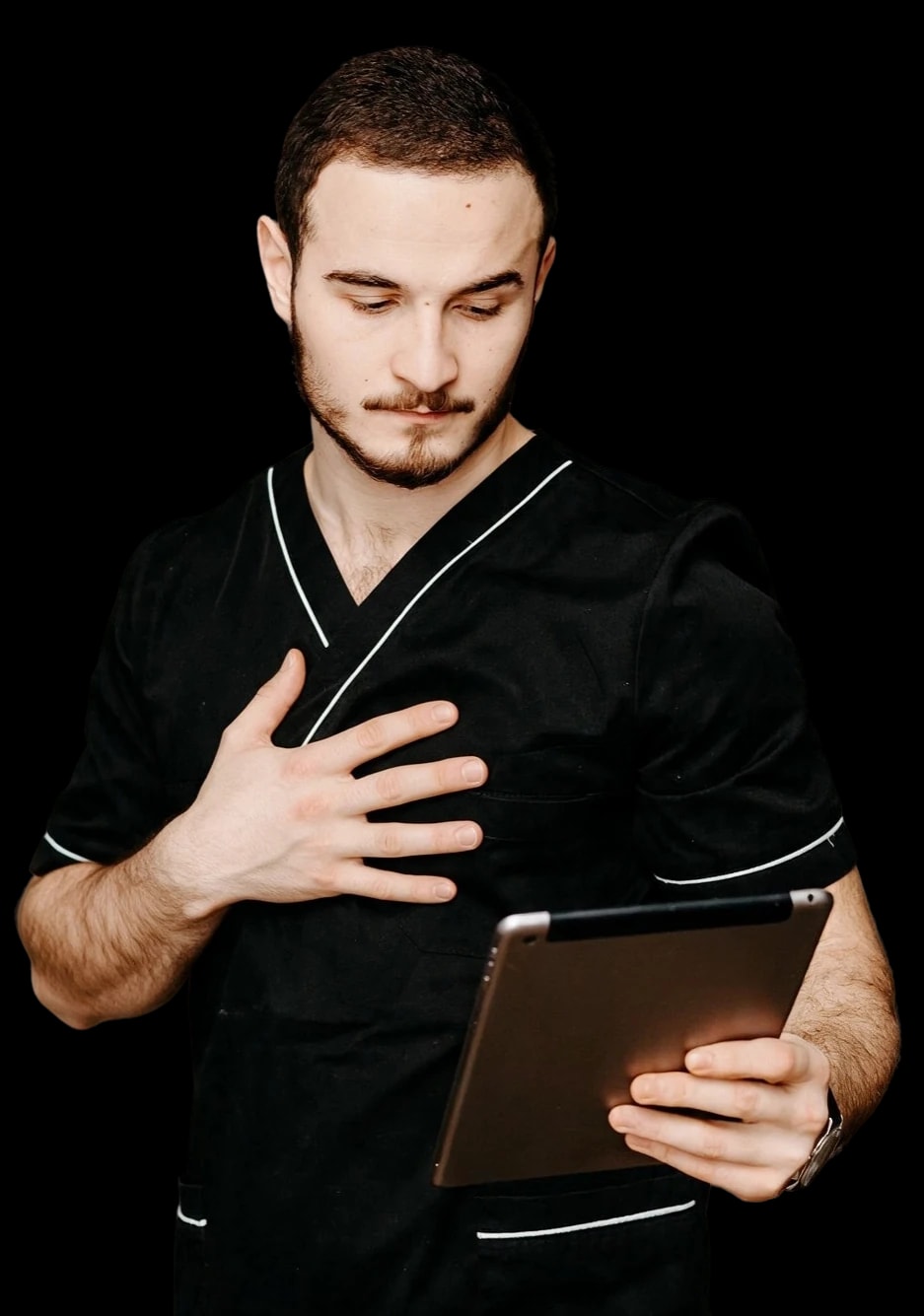 A nurse in black scrubs looking down at a tablet.
