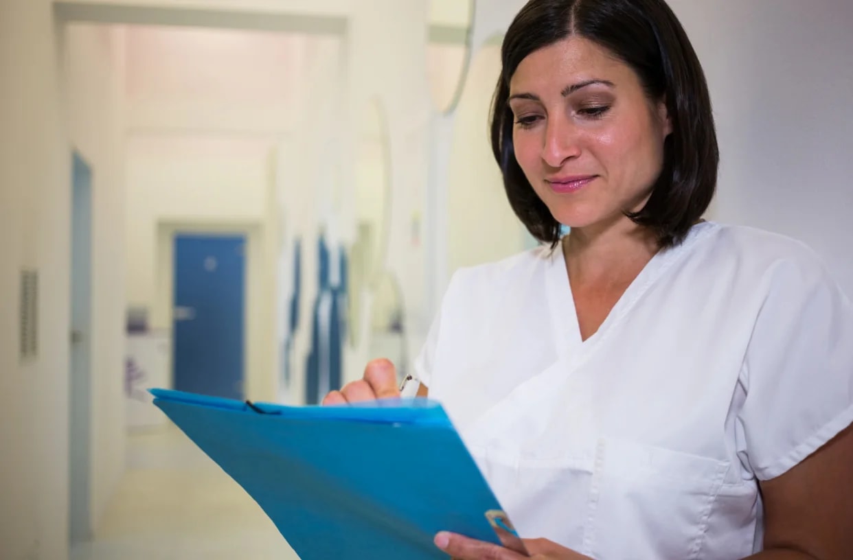 A confident healthcare assistant in uniform, smiling.